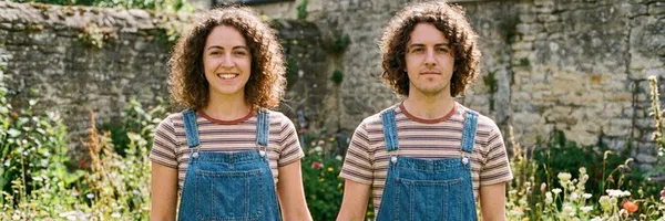 Två tvillingar i likadana kläder som är lika som bär, den ene är en man, den andra är en kvinna.