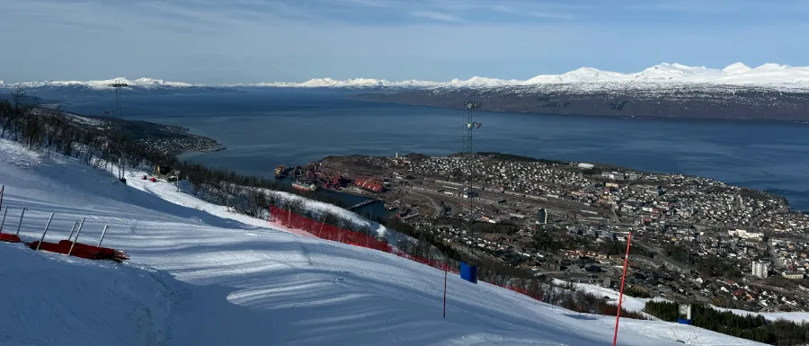 Utsikt från toppen av backen i Narvik. Fjorden breder ut sig med snötäckta berg och vackert hav.