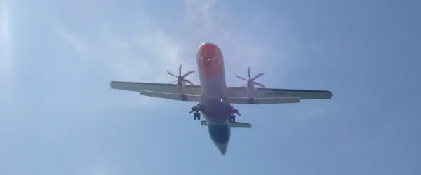 Ett propellerplan kommer in för landning ovanför våra huvuden på Mai Khao Beach i Thailand