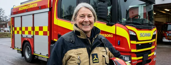 En brandman, eller snarare en brandkvinna, står framför ett arbetsfordon. Ingen söndagsångest här inte!